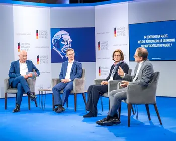 Vier Personen sitzen auf einer Bühne bei einer Podiumsdiskussion.