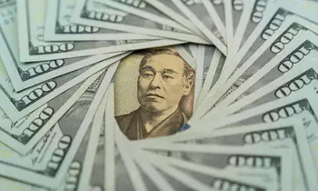Eine japanische 10.000-Yen-Banknote liegt in der Mitte, kreisförmig umgeben von aufgefächerten 100-US-Dollar-Scheinen.