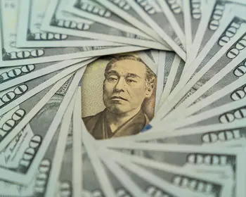 Eine japanische 10.000-Yen-Banknote liegt in der Mitte, kreisförmig umgeben von aufgefächerten 100-US-Dollar-Scheinen.