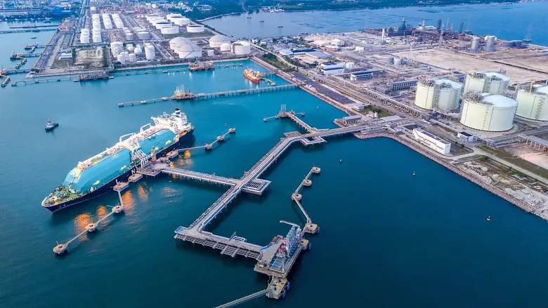LNG-Tanker am Terminal mit Speicherbehaeltern und Industrieanlagen an der Küste.