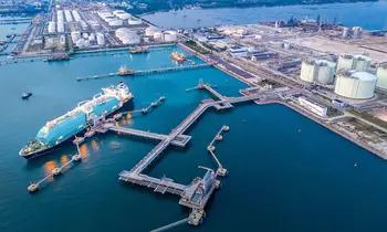 LNG-Tanker am Terminal mit Speicherbehaeltern und Industrieanlagen an der Küste.