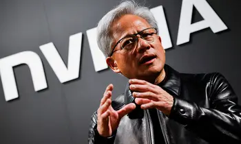 Jensen Huang mit grauen Haaren und Brille, in schwarzer Lederjacke, gestikulierend vor einer Wand mit dem NVIDIA-Schriftzug.
