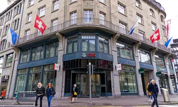 Eingang einer UBS-Filiale an der Bahnhofstrasse in Zürich mit Passanten und Schweizer Fahnen.