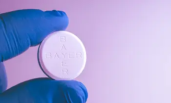 Tablette von Bayer zwischen den Fingern. 